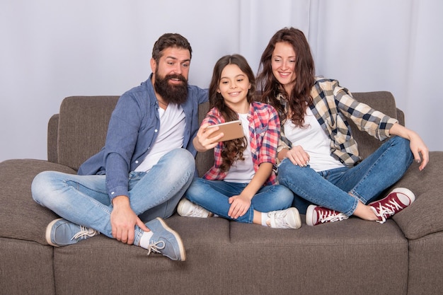 Uomo e donna felici che sorridono mentre il bambino riprende video sulla famiglia di smartphone