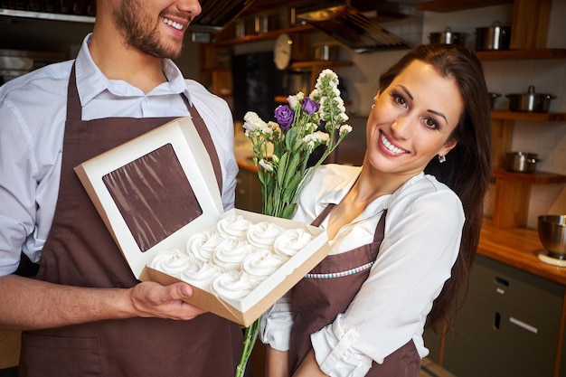 Uomo e donna in grembiuli in pasticceria o cucina di panetteria. Prodotti dolciari preparazione professionale