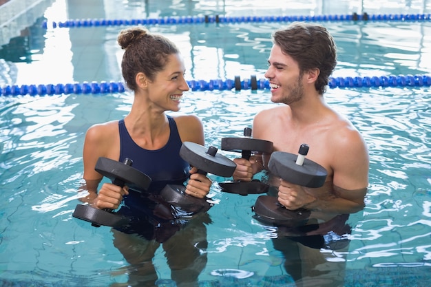 Uomo e donna in piedi con manubri schiuma in piscina