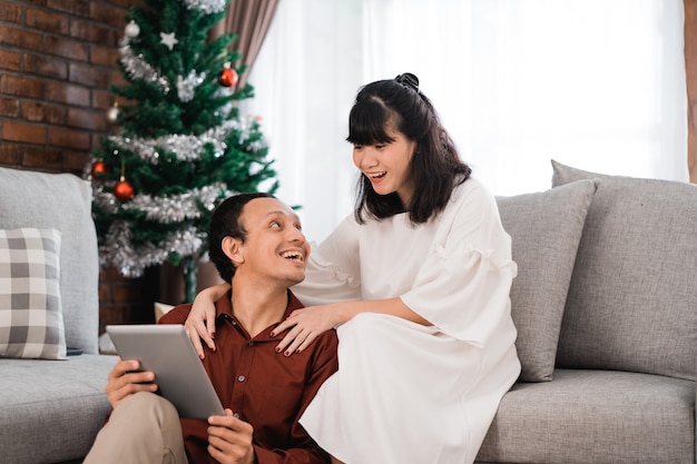 Uomo e donna in soggiorno insieme utilizzando tablet pc durante il giorno di Natale