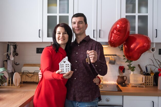 Uomo e donna innamorati data a casa in cucina con le chiavi di casa San Valentino coppia felice storia d'amore Nido d'amore mutuo trasferimento acquisto immobiliare alloggio per giovane famiglia