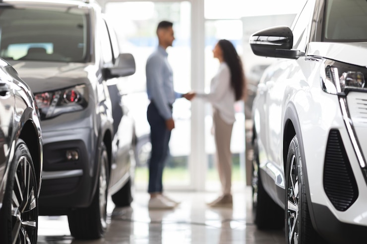 Foto uomo e donna irriconoscibili che si stringono la mano allo showroom automobilistico