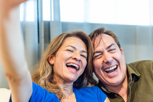 Uomo e donna maturi sorridenti che prendono un selfie. Foto di alta qualità