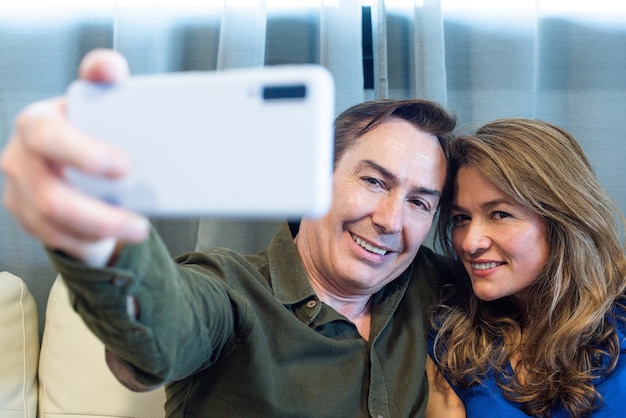 Uomo e donna maturi sorridenti che prendono un selfie. Foto di alta qualità