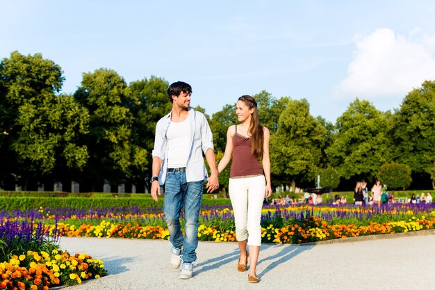 Uomo e donna o giovane coppia che fa un viaggio come turisti nel parco camminando mano nella mano