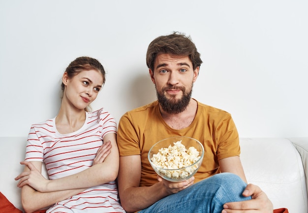 Uomo e donna sul divano con popcorn a guardare programmi TV