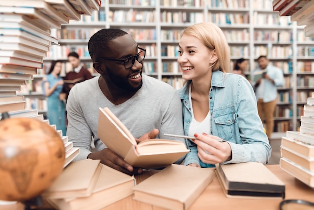 Uomo e ragazza bianca che si siedono alla tabella circondata dai libri.