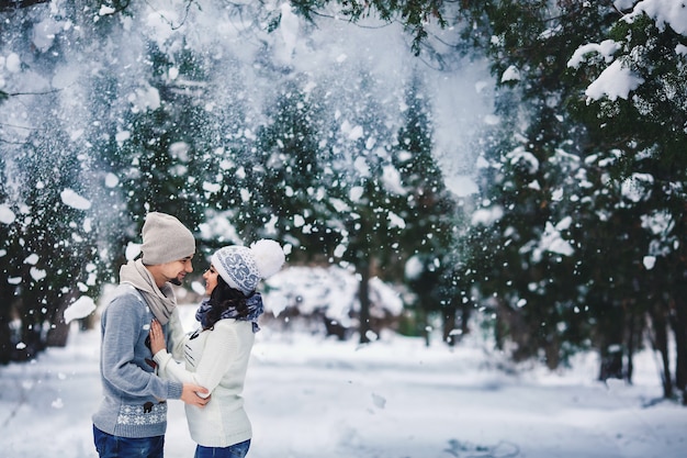 Uomo e ragazza in maglioni che abbracciano nel parco in inverno. passeggiata invernale, riposo.