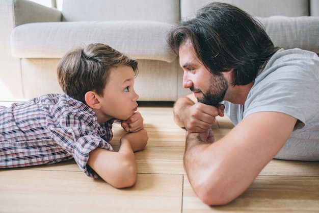 Uomo e ragazzo seri e concentrati sono distesi sul pavimento e si guardano