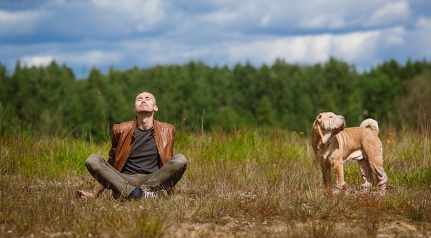 Uomo e un cane di razza shar pei seduto per terra