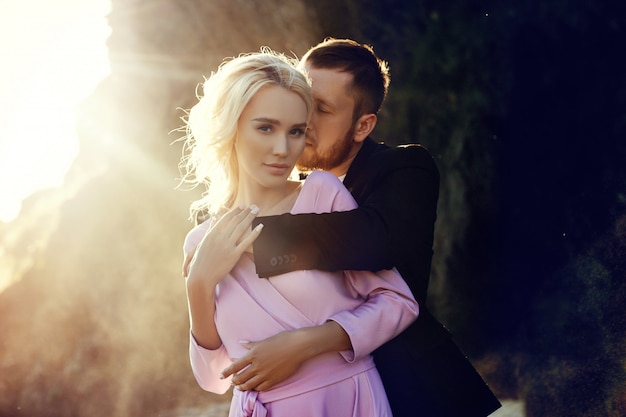 Uomo e una donna che abbraccia in estate al tramonto in bei vestiti.