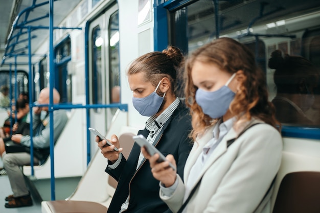 uomo e una donna con smartphone seduti in un vagone della metropolitana