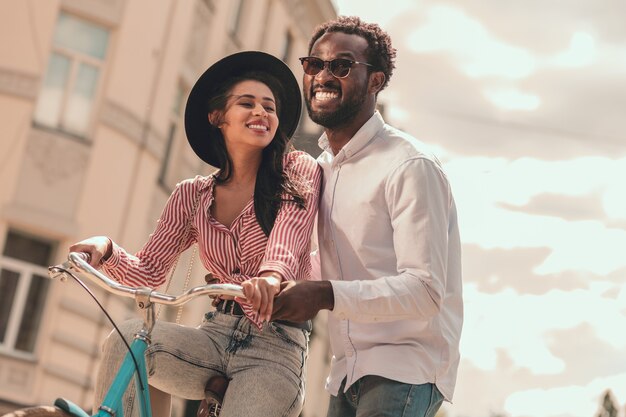 Uomo eccitato che sorride e aiuta la sua ragazza ad andare in bicicletta