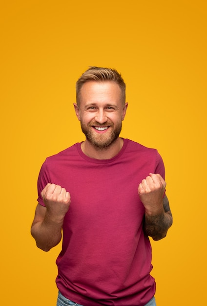 Uomo eccitato che stringe i pugni e sorride alla macchina fotografica