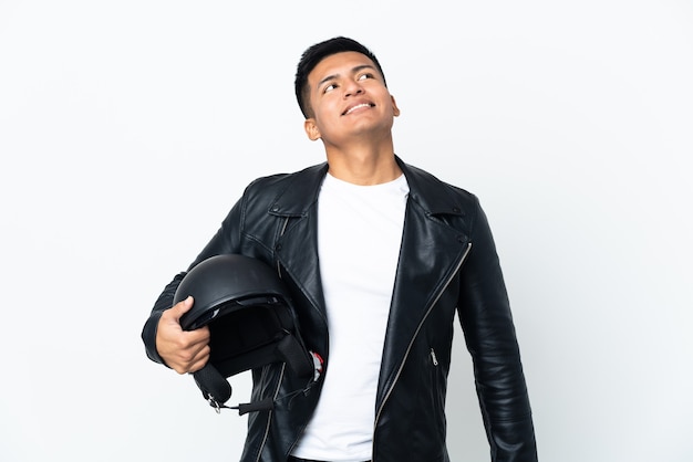 Uomo ecuadoriano con un casco da motociclista isolato su sfondo bianco che pensa a un'idea mentre guarda in alto