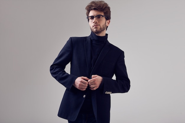 Uomo elegante bello con i capelli ricci che indossa abito e occhiali