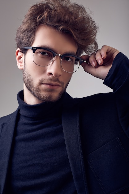 Uomo elegante bello con i capelli ricci che indossa abito e occhiali