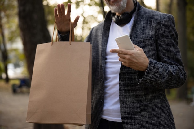 Uomo elegante che cammina nel parco dopo lo shopping