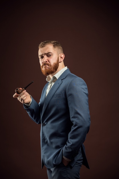 Uomo elegante con la barba che tiene il tubo di fumo