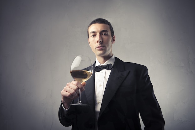 Uomo elegante in tuta in possesso di un vino