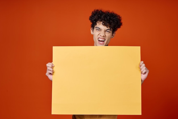 Uomo emotivo con poster di capelli ricci gialli nelle mani