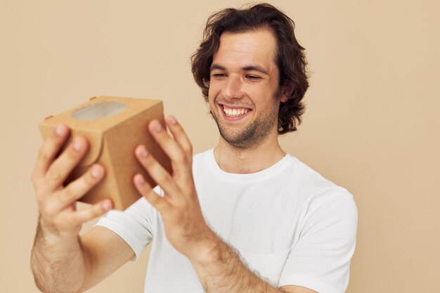 Uomo emotivo con scatola regalo su sfondo beige