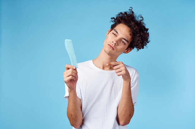 Uomo emotivo con un pettine in mano e capelli ricci in uno spazio di copia di sfondo blu