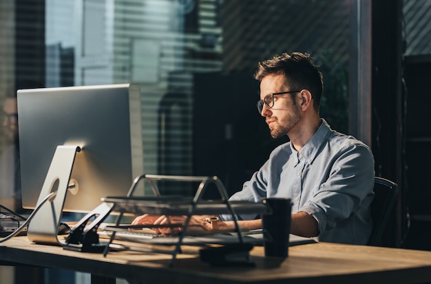 Uomo esaurito che lavora fuori orario in ufficio