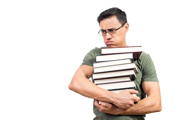 Uomo esausto con gli occhiali che trasportano una pila di libri di testo ed espirano durante la preparazione dell'esame su sfondo bianco