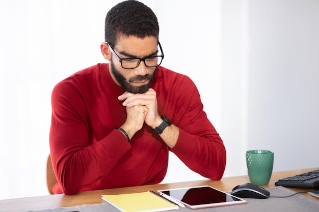 Uomo esausto seduto alla scrivania in ufficio utilizzando il pad digitale