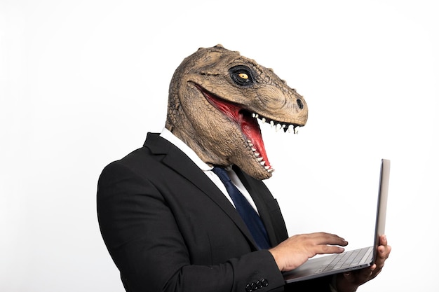 Uomo esecutivo con testa t rex usando il suo laptop su sfondo bianco isolato