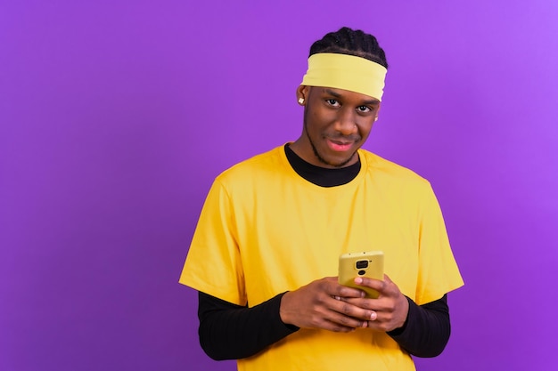 Uomo etnico nero con un telefono in abiti gialli su sfondo viola