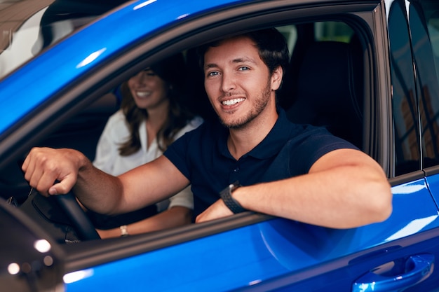 Uomo felice alla guida di auto in concessionaria