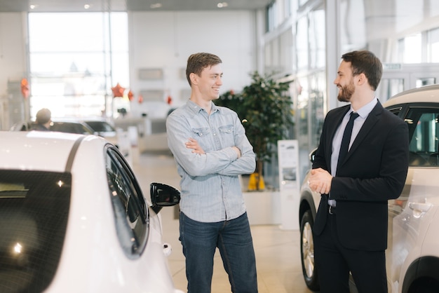 Uomo felice allegro che si prepara ad acquistare una nuova auto in una concessionaria auto