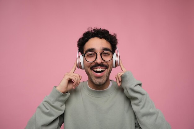 Uomo felice che balla e ascolta musica in cuffia che punta alle orecchie