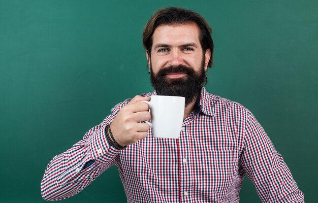 Uomo felice che beve il caffè del mattino dalla tazza su energia di fondo verde