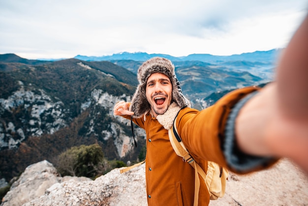 Uomo felice che cattura un selfie scalando le montagne