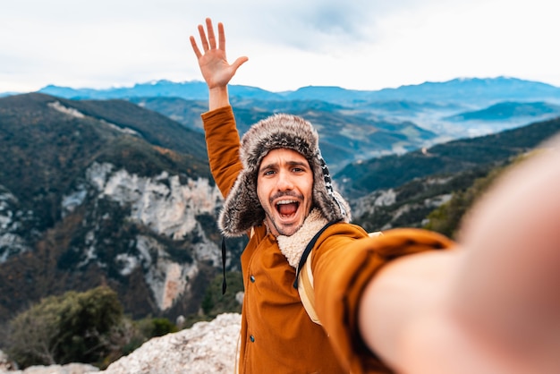 Uomo felice che cattura un selfie scalando le montagne