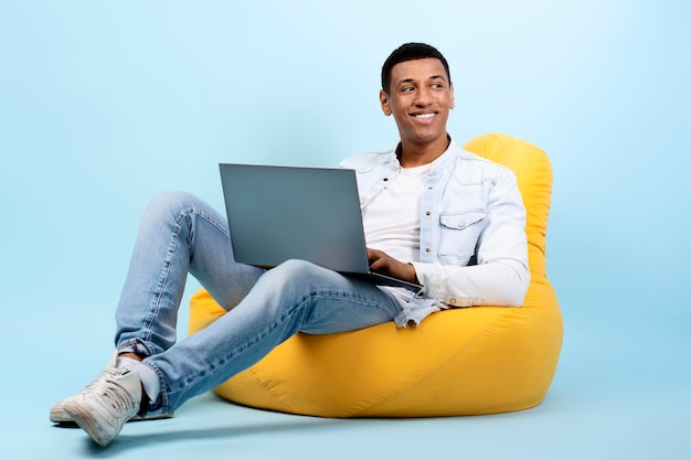 Uomo felice che distoglie lo sguardo digitando il contenuto delle informazioni utilizzando il laptop per lavorare