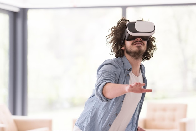 uomo felice che fa esperienza usando gli occhiali VR-auricolare della realtà virtuale a casa