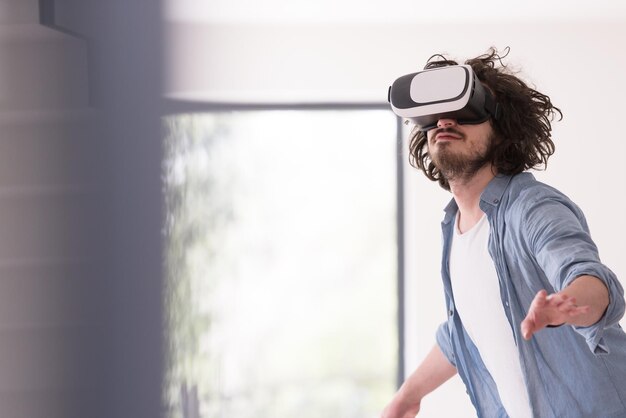 uomo felice che fa esperienza usando gli occhiali VR-auricolare della realtà virtuale a casa