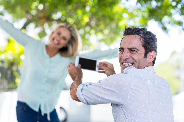 Uomo felice che fotografa donna