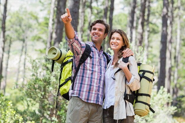 Uomo felice che indica mentre levandosi in piedi con il socio in foresta