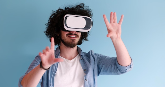 Uomo felice che ottiene esperienza utilizzando gli occhiali per cuffie VR della realtà virtuale, isolati su sfondo blu