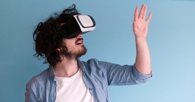 Uomo felice che ottiene esperienza utilizzando gli occhiali per cuffie VR della realtà virtuale, isolati su sfondo blu