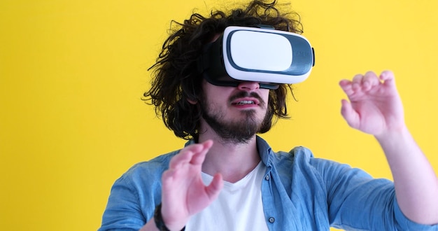 Uomo felice che ottiene esperienza utilizzando gli occhiali per cuffie VR della realtà virtuale, isolati su sfondo giallo