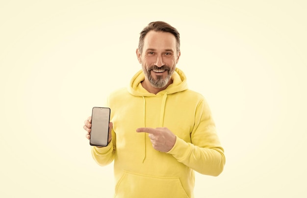 Uomo felice che presenta lo schermo dello smartphone che punta il dito sullo spazio di copia che presenta il prodotto