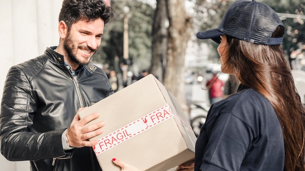 Uomo felice che riceve il pacco dal corriere femminile