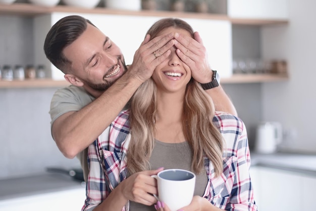 Uomo felice che scherza con la sua ragazza in cucina al mattino