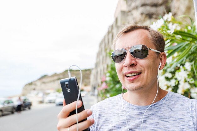 Uomo felice che sorride e che chiama dal telefono cellulare sulla spiaggia